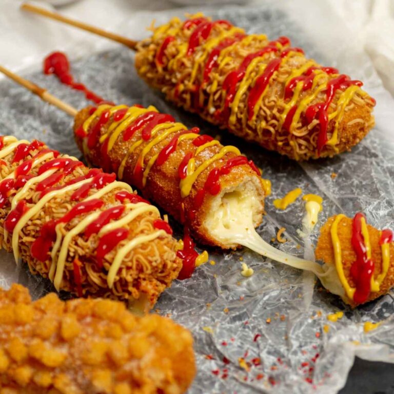 Three Korean corn dogs with cheese oozing out of the middle