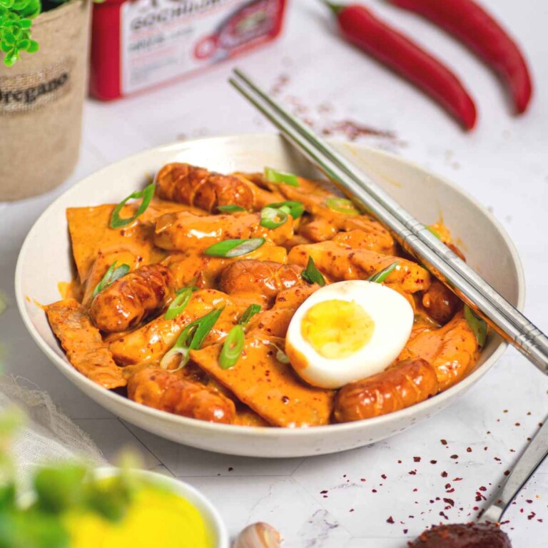 Rose tteokbokki with egg on top in a deep plate