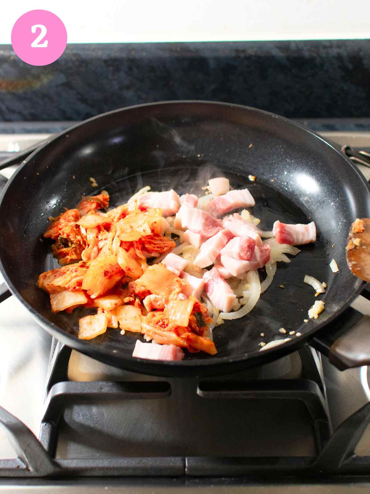 kimchi, pork belly and onion in black pan
