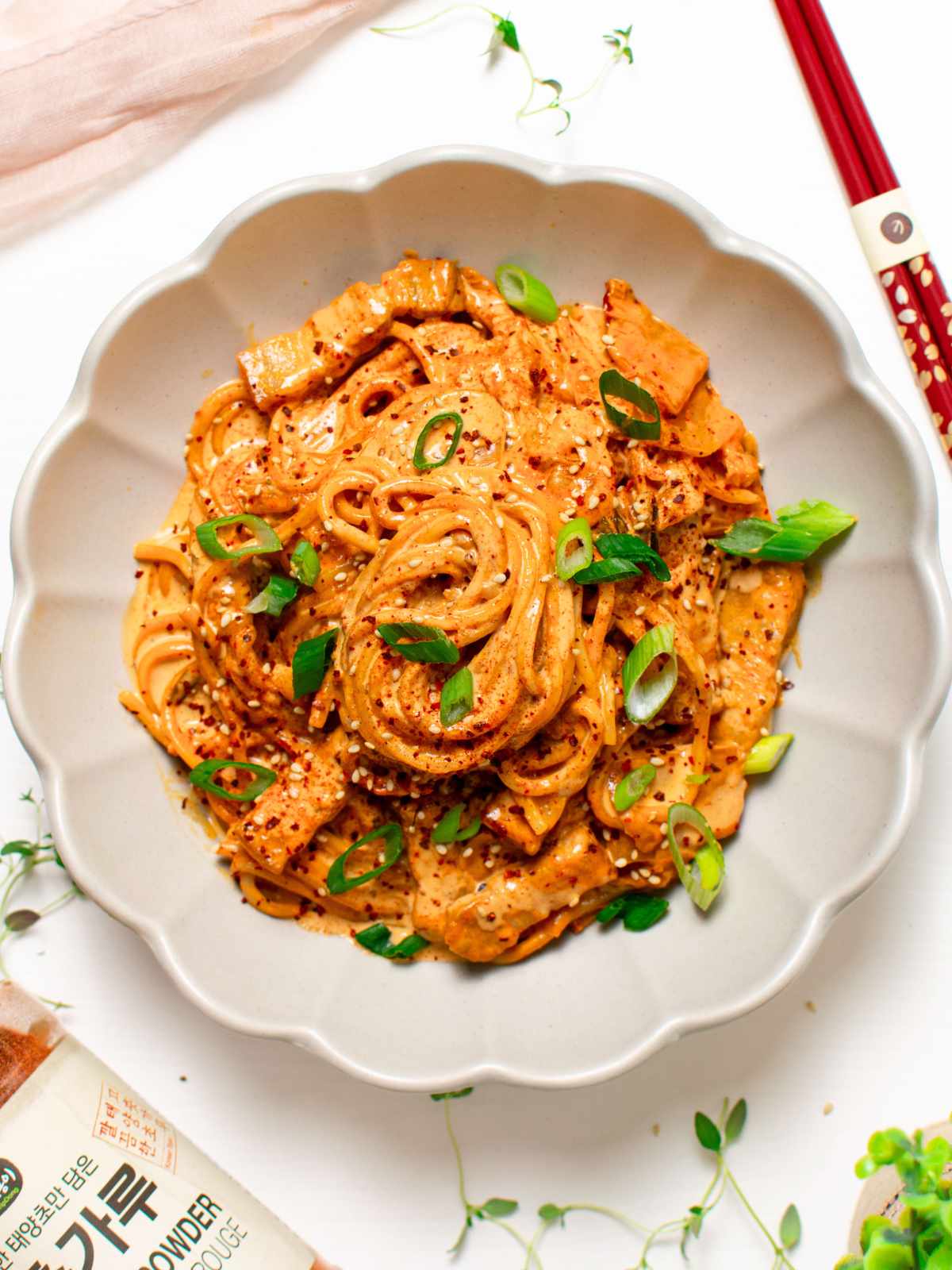 Creamy kimchi udon noodles in bowl with green onion slices on top