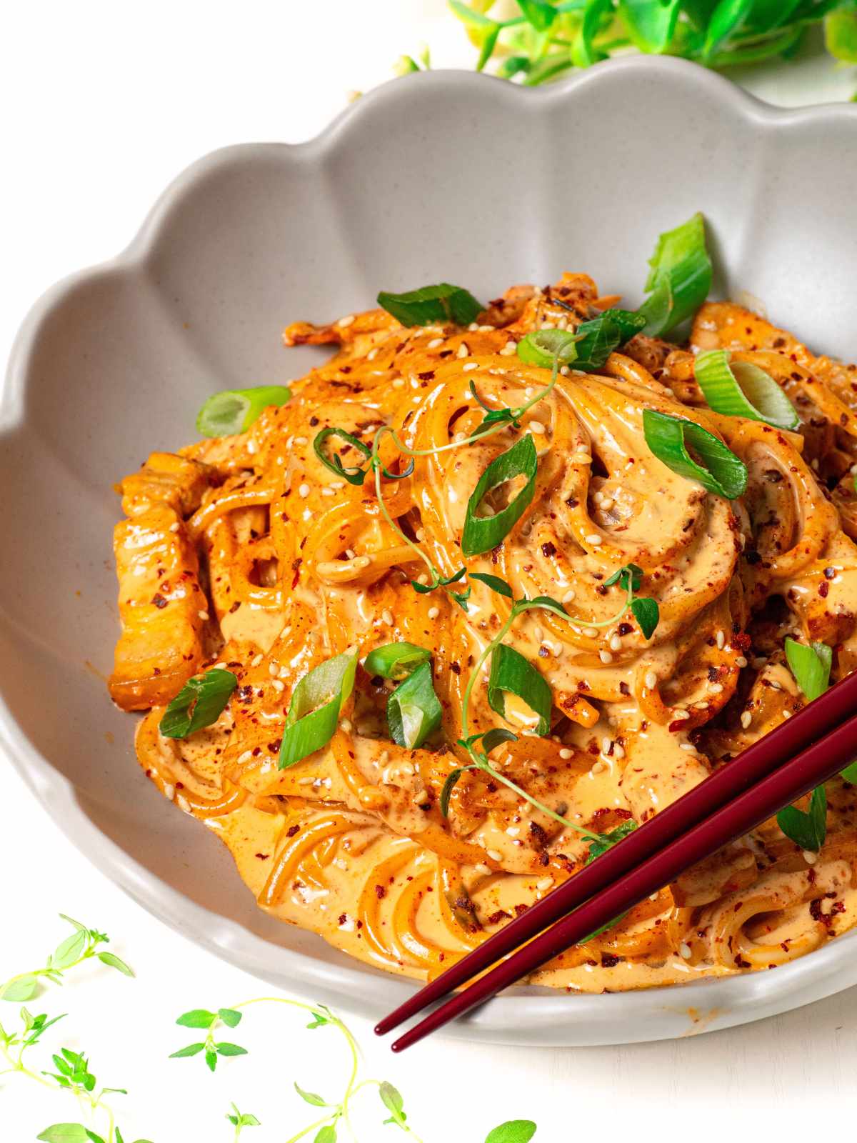 Creamy kimchi udon noodles in scallop shape bowl with chopsticks on top