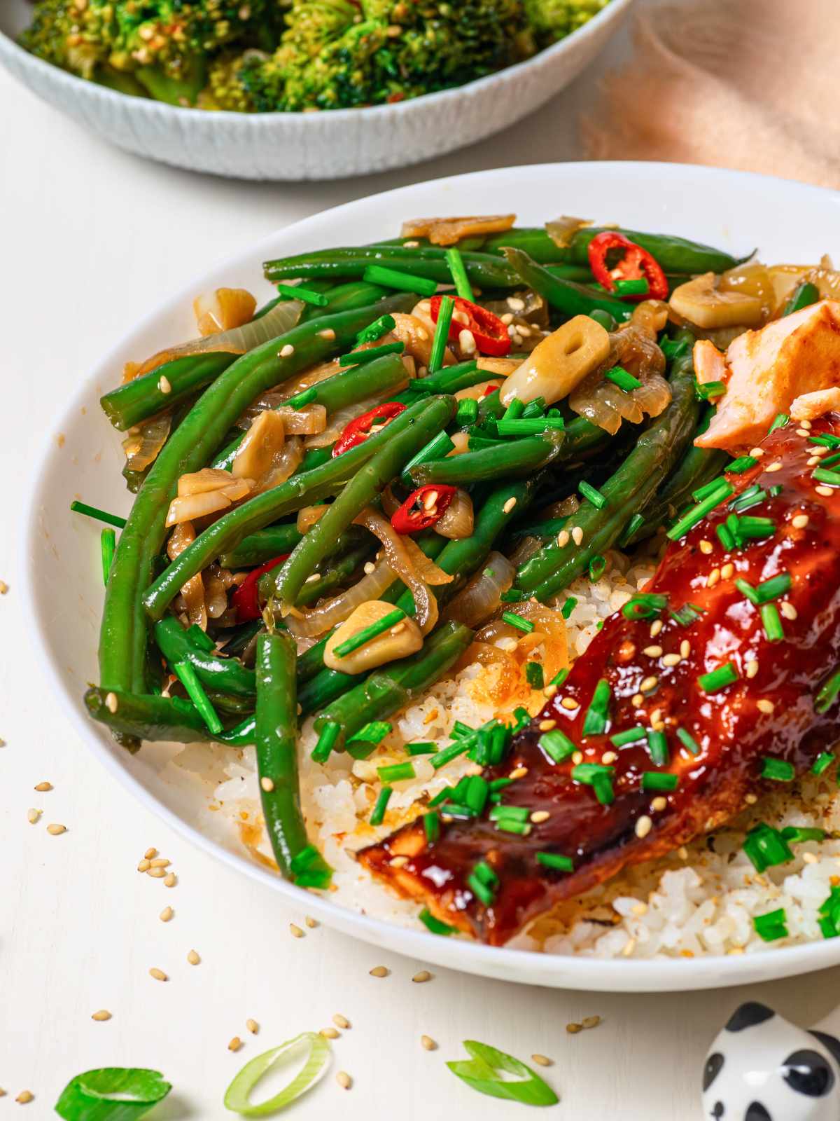 Korean green beans on top of rice next to salmon on plate