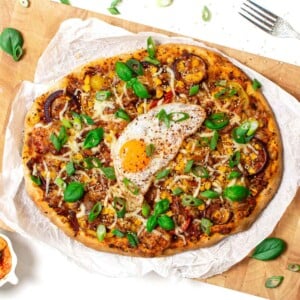 Kimchi pizza with fried egg on top on wooden board