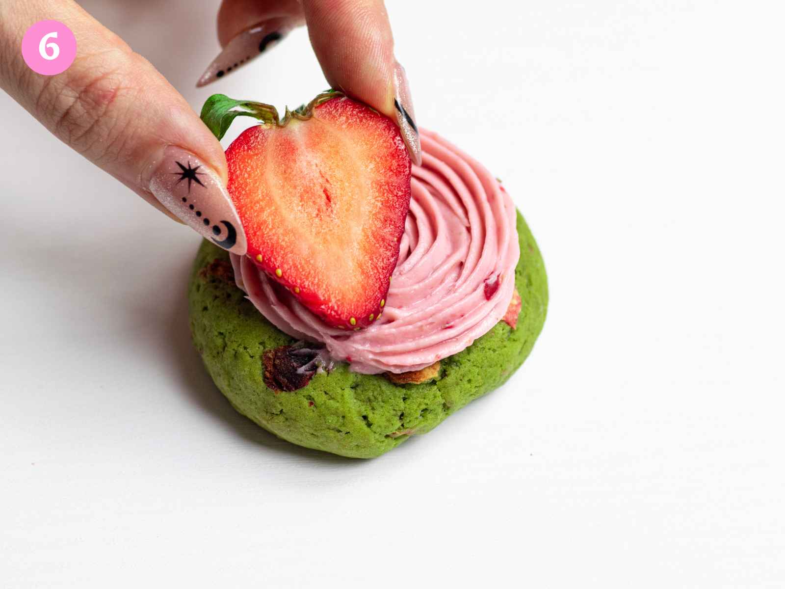Placing strawberry half on top of matcha strawberry cookie