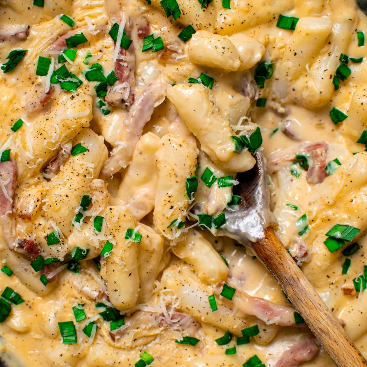 Carbonara tteokbokki, chewy rice cakes in a creamy sauce with bacon, parmesan and chopped spring onion